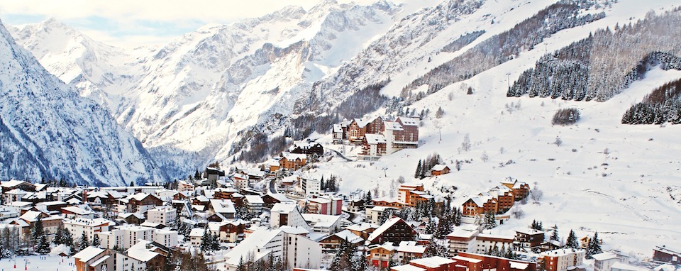 Panoramaansicht eines verschneiten Bergdorfes mit zahlreichen Gebäuden, eingebettet in eine schneebedeckte Alpenlandschaft, potenzieller Anwendungsbereich für geotechnical monitoring zur Erfassung geologischer Stabilität